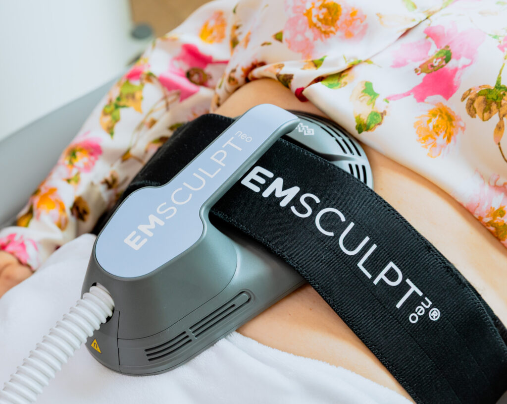 Emsculpt NEO applicator placed on woman's stomach to add muscle tone and reduce fat in the abdominal area. This is an alternative treatment to a belly tuck in St. Lucie County.